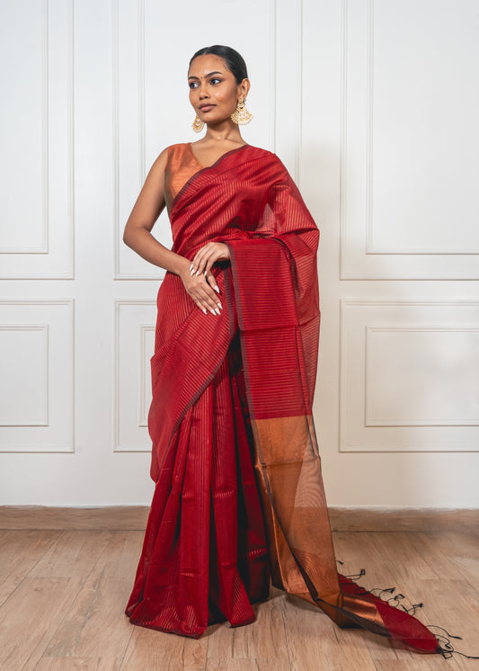 Red Maheshwari cotton silk saree with golden zari pallu and crisp pleats—capturing regal contrast and woven finesse