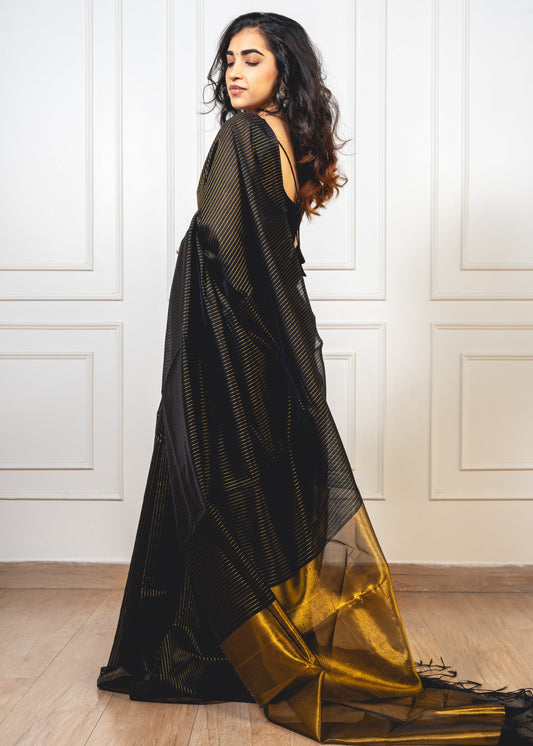 Woman wearing black Maheshwari cotton saree with gold zari lines and pallu—styled for festive grace and timeless elegance.