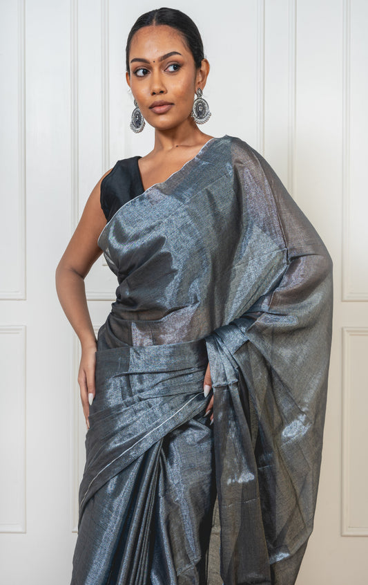 Woman wearing Ash Grey Tissue Silk Saree with soft pleats and shimmering pallu, styled for festive elegance and modern grace.