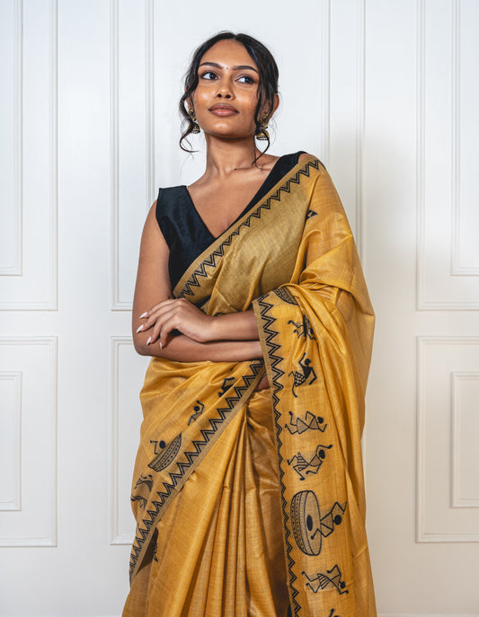Close-up of black Warli embroidery on sandalwood yellow cotton silk saree—highlighting tribal artistry and fine craftsmanship
