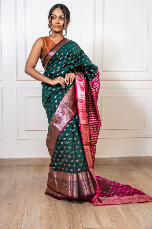 Peacock green saree with flowing pallu and vibrant red border—capturing graceful movement and regal elegance.