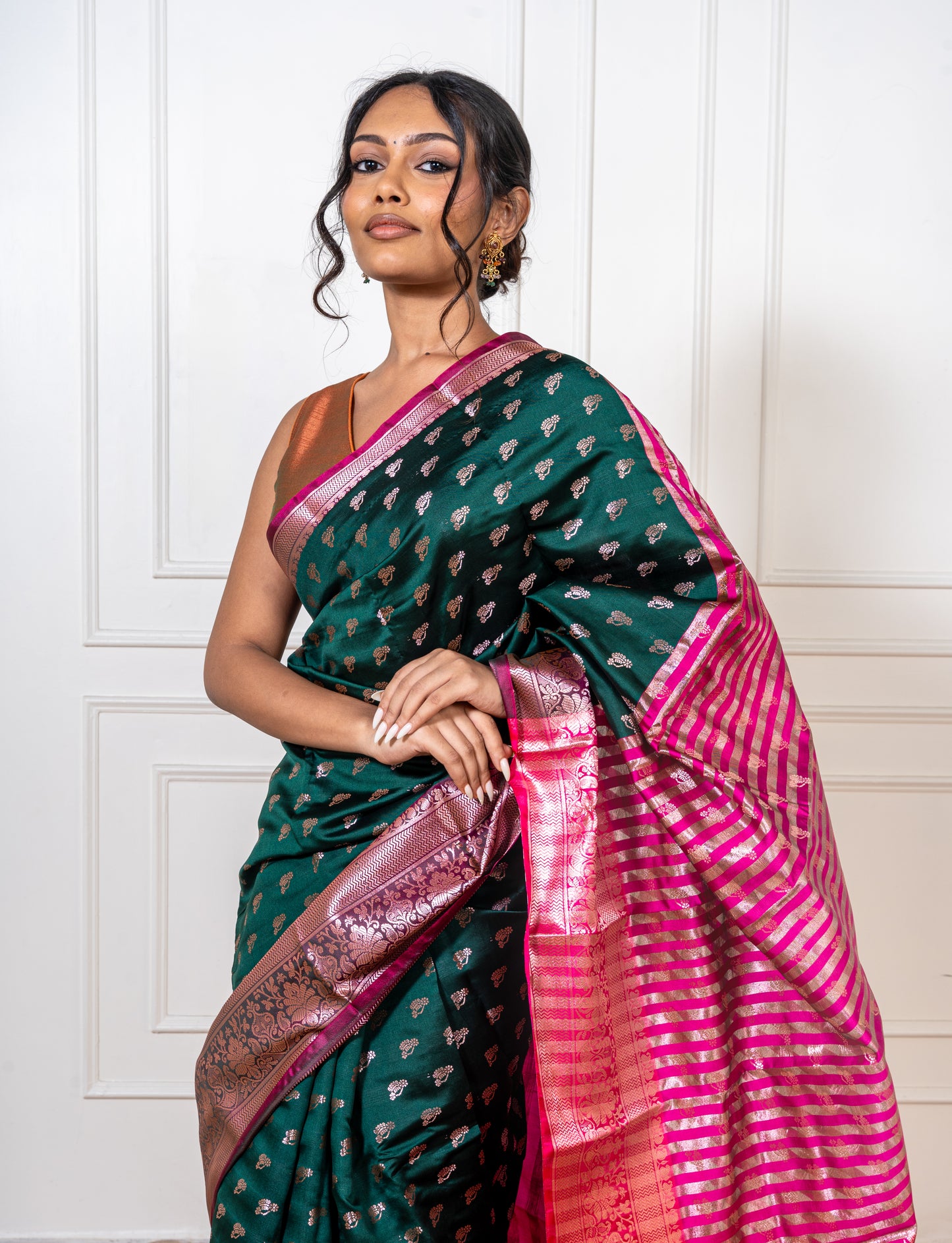 Close-up of golden zari on peacock green saree—highlighting intricate craftsmanship and jewel-toned shimmer.