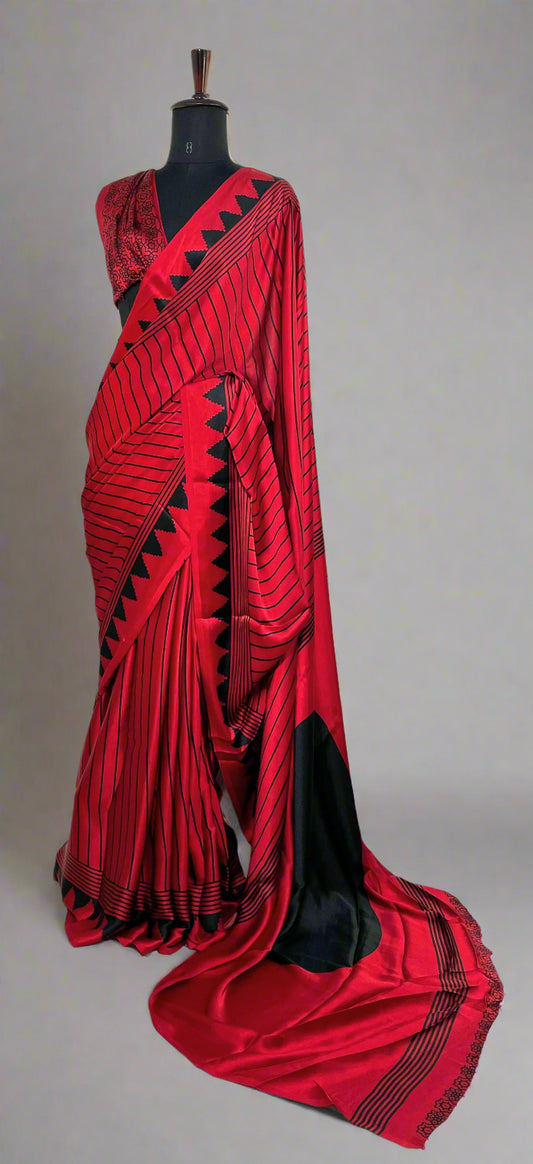 Red Modal silk saree with black-printed pallu and crisp pleats—capturing graceful movement and graphic charm.