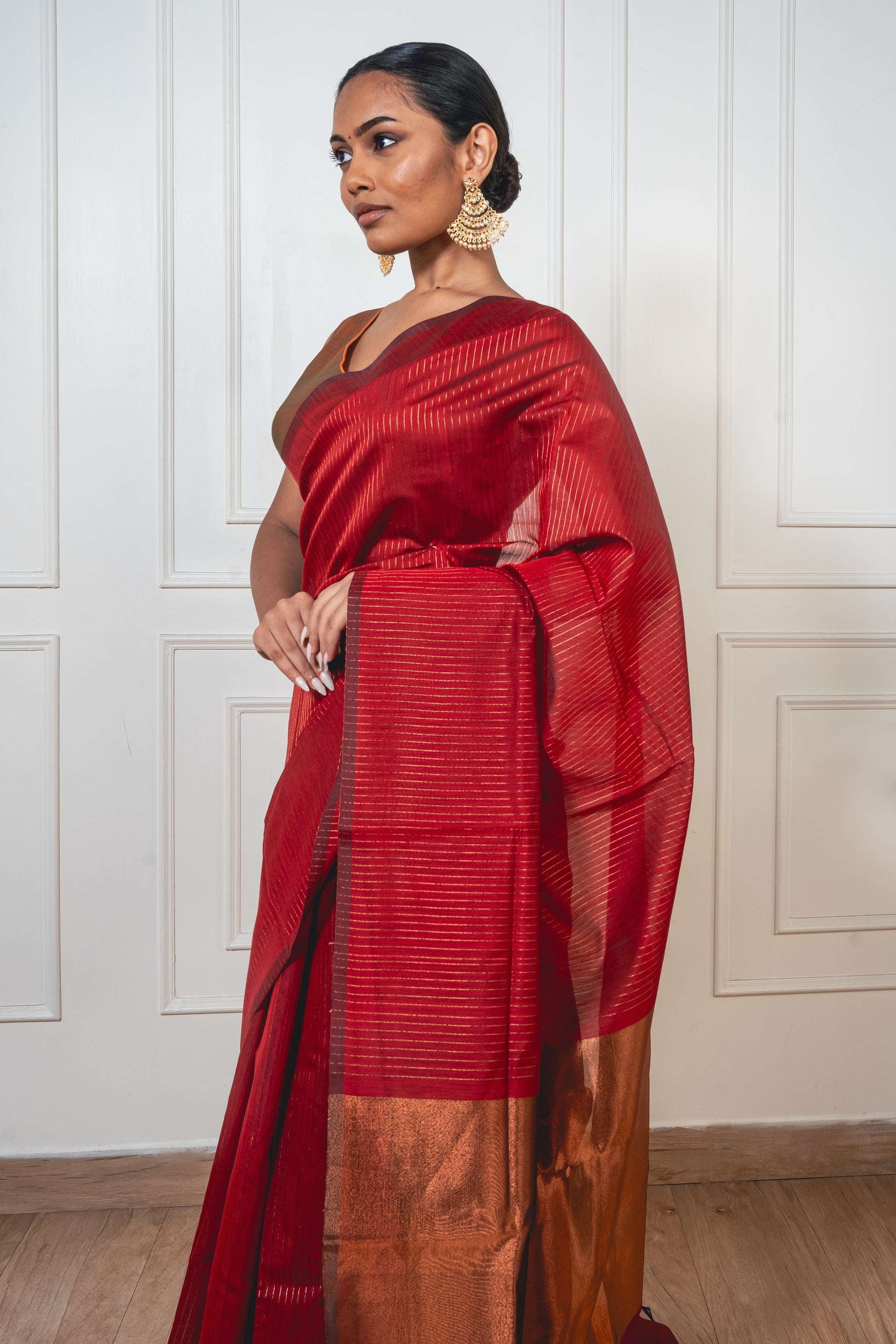 Close-up of golden zari lines on red Maheshwari cotton silk saree—highlighting intricate weave and radiant shimmer.