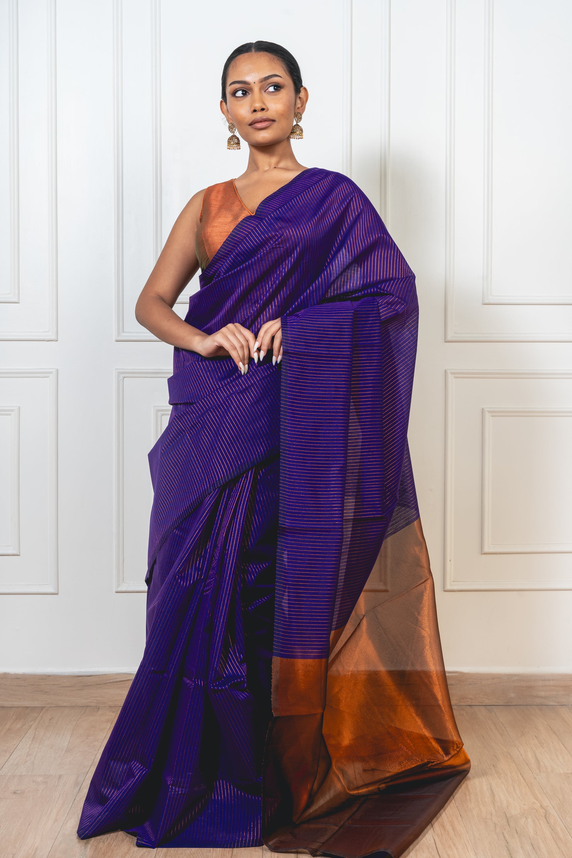 Woman wearing blue Maheshwari cotton silk saree with copper zari lines and pallu—styled for festive grace and traditional charm.