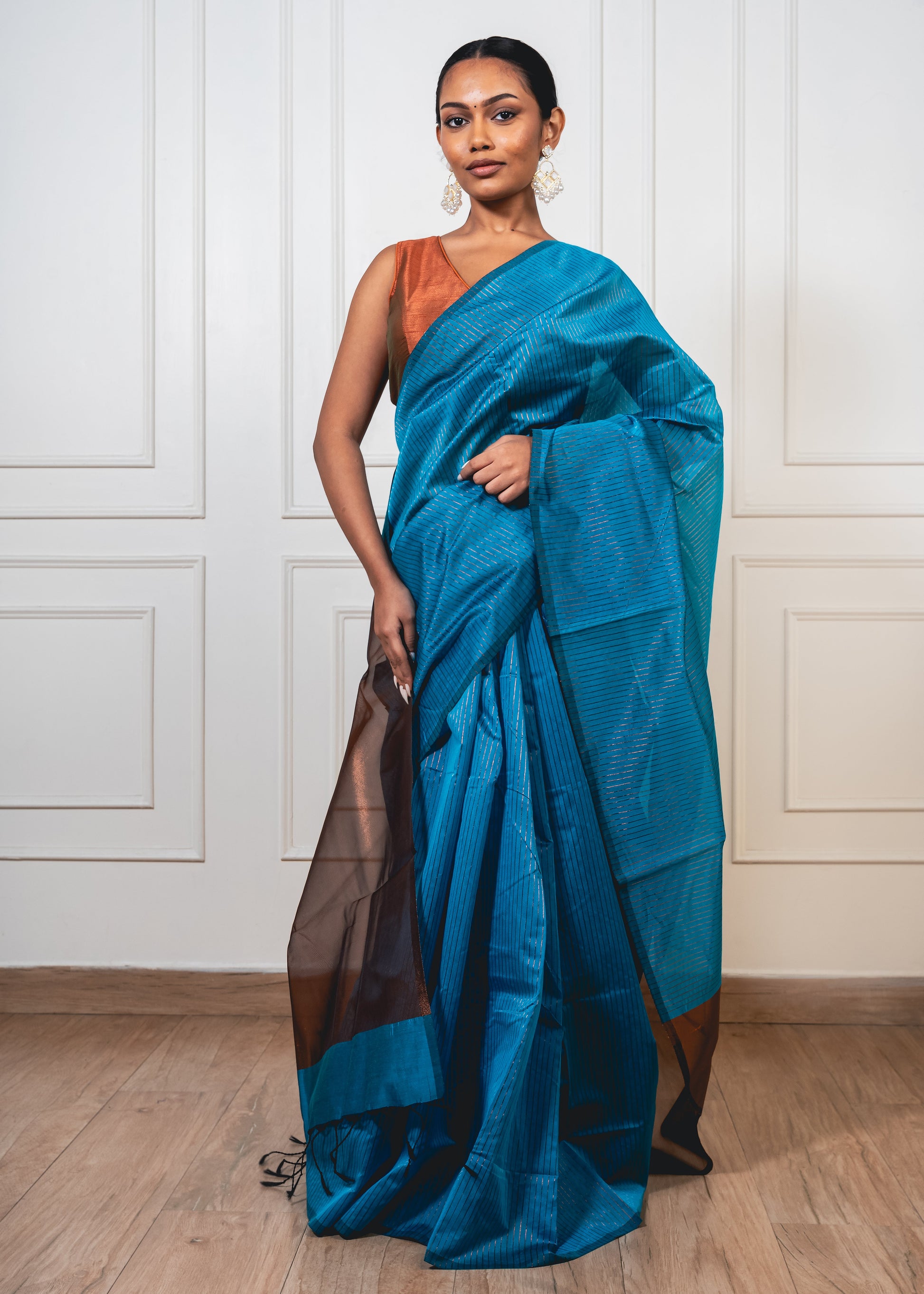 Woman wearing light blue Maheshwari cotton silk saree with copper zari lines and pallu—styled for festive grace and artisanal charm.