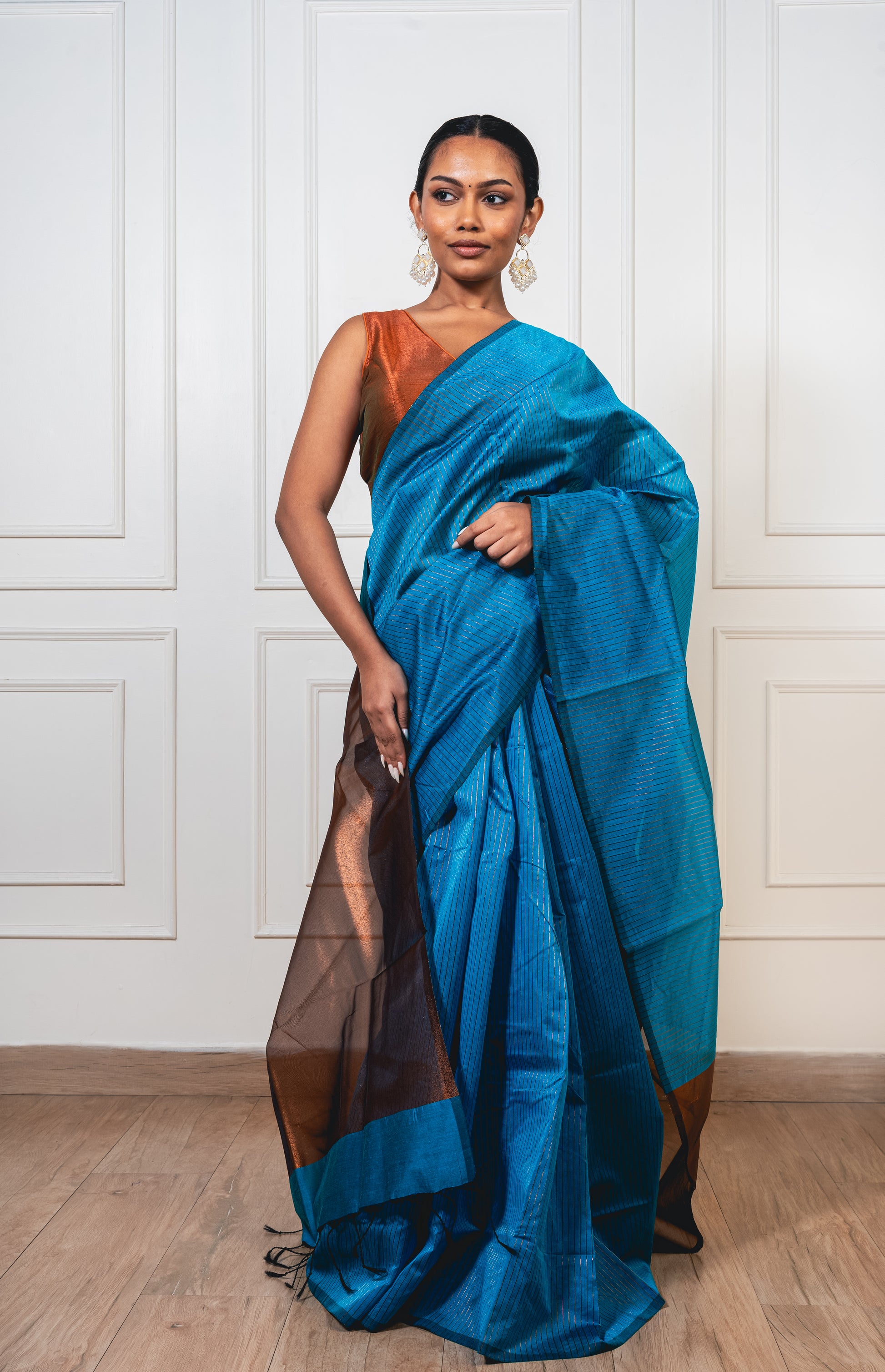 Light blue Maheshwari cotton silk saree with copper zari pallu and crisp pleats—capturing serene elegance and woven richness.