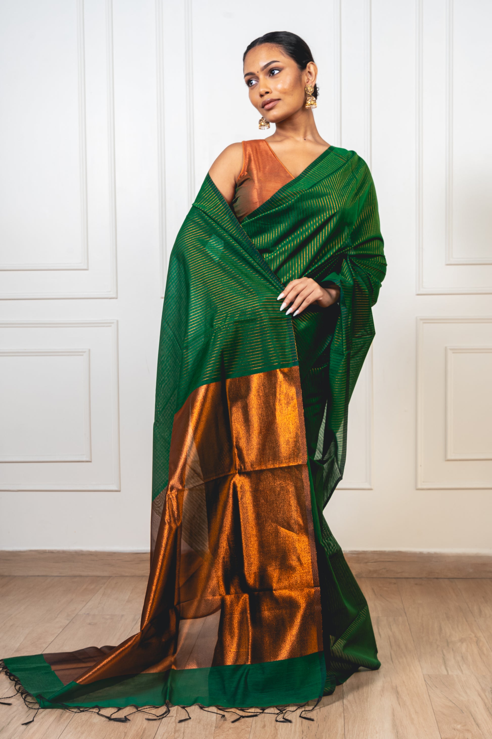 Woman wearing green Maheshwari cotton silk saree with copper zari lines and pallu—styled for festive grace and artisanal charm.