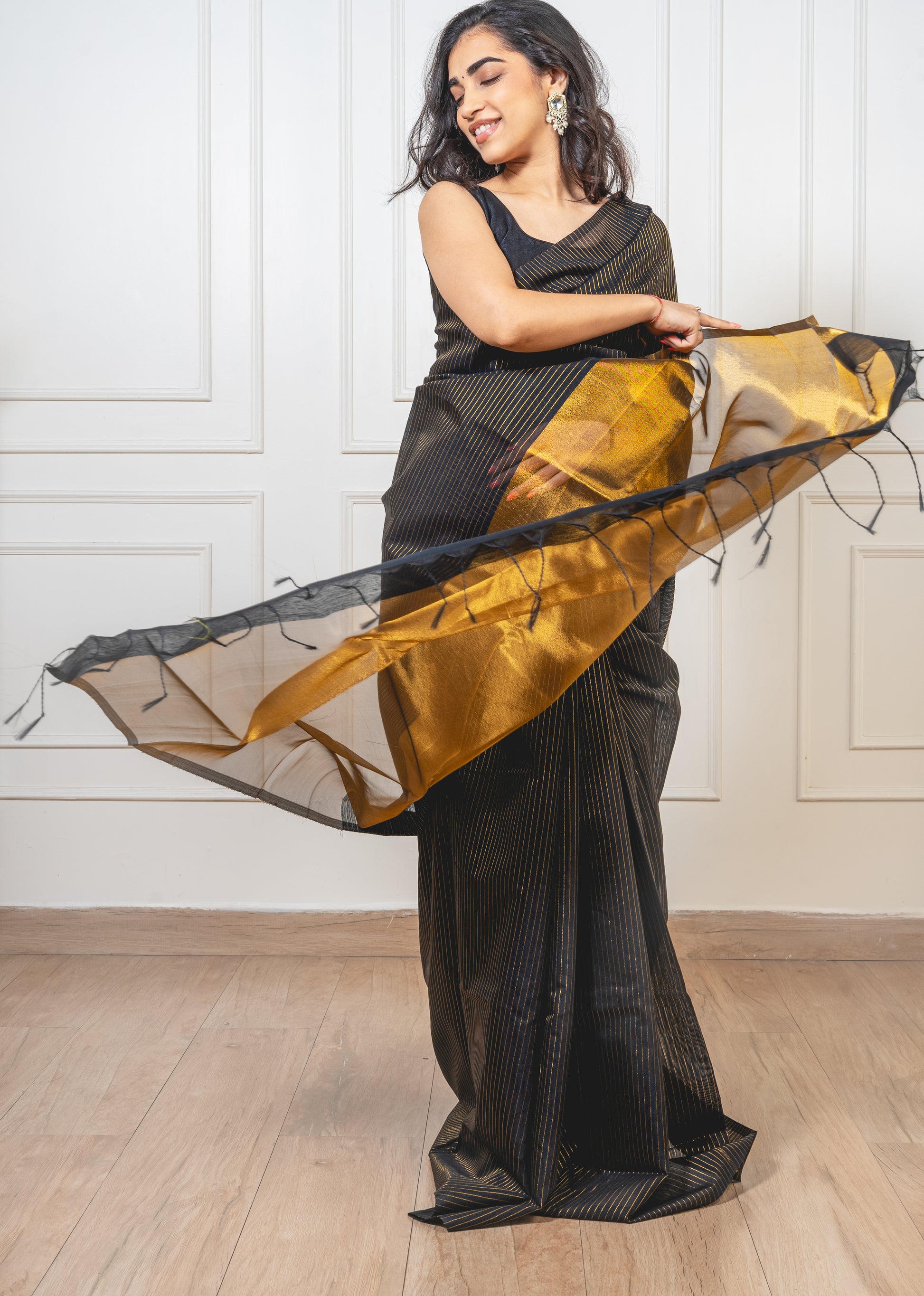 Black Maheshwari cotton saree with gold zari pallu and crisp pleats—capturing regal contrast and artisanal finesse
