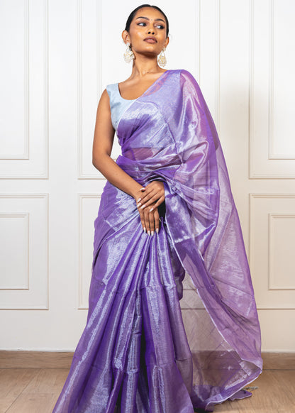 Woman wearing periwinkle purple tissue silk saree—styled for festive evenings, graceful rituals, and timeless elegance.