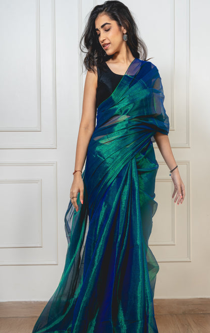 Peacock green tissue silk saree laid flat—showcasing seamless silhouette and shimmering texture.