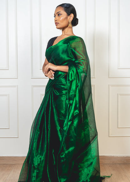 Woman wearing emerald green tissue silk saree—styled for festive elegance with sheer texture and graceful movement.