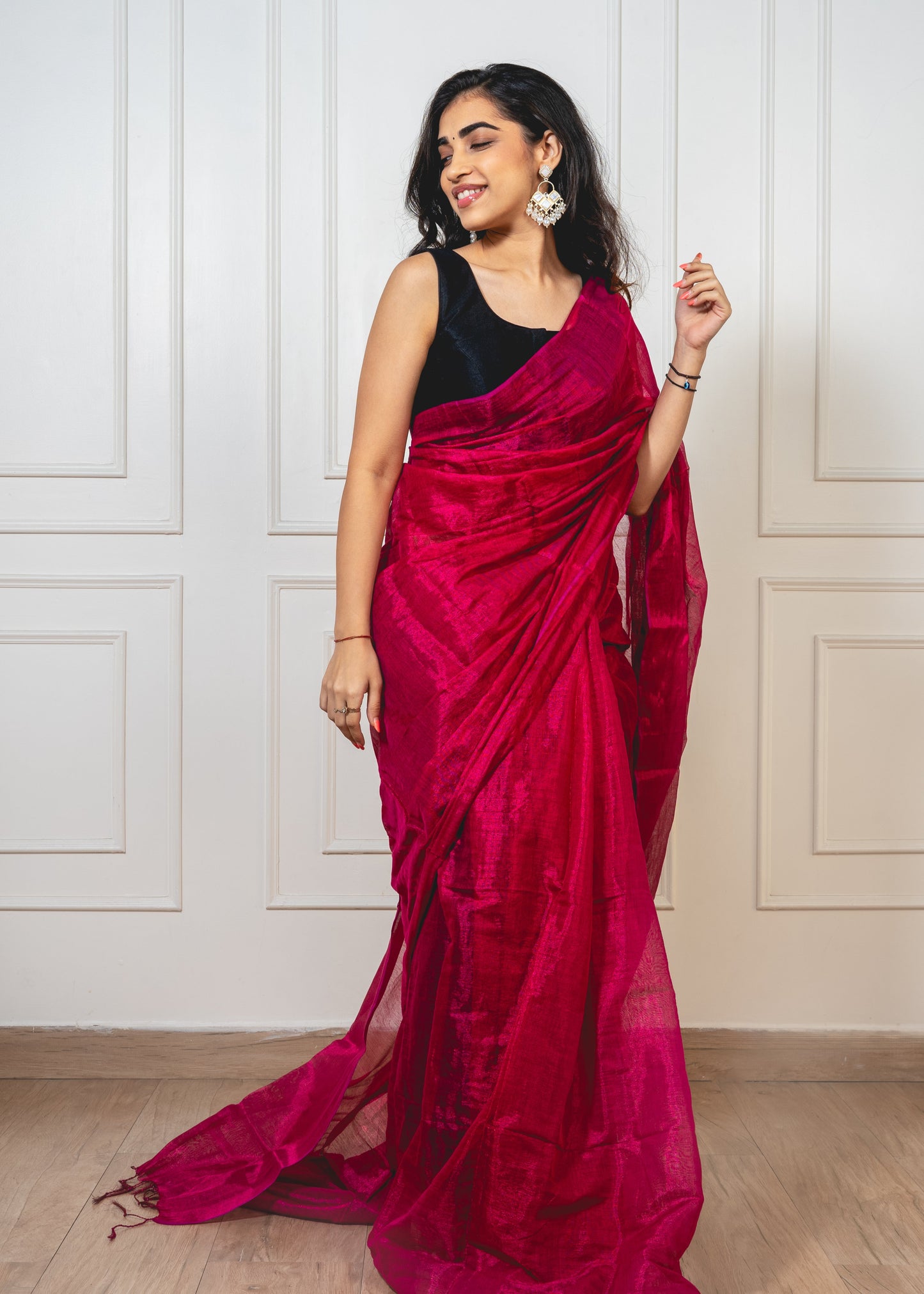 Woman wearing cherry red tissue silk saree—styled for festive radiance with sheer texture and graceful drape.