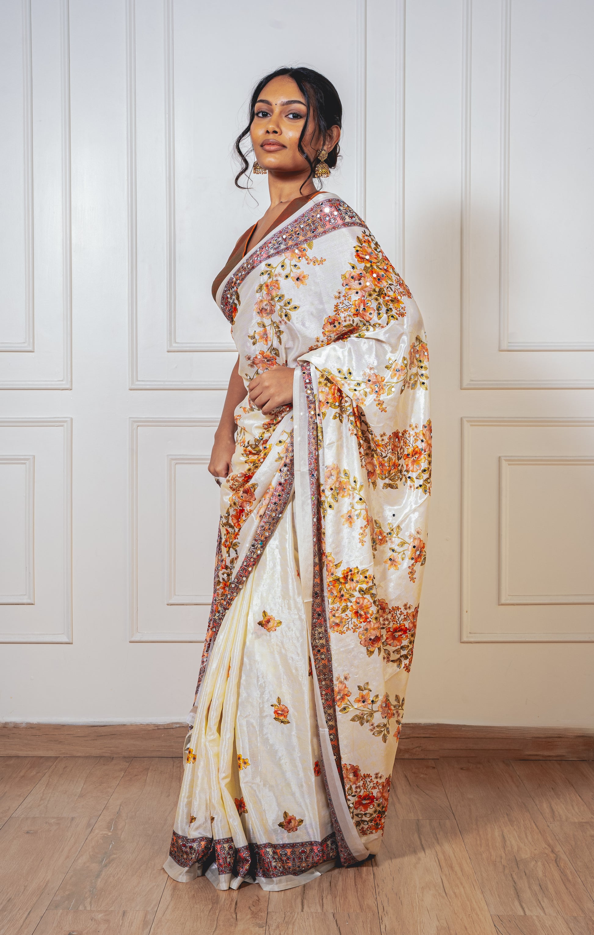 Floral white Chinon silk saree with mirror-detailed pallu and crisp pleats—capturing festive shimmer and graceful movement.