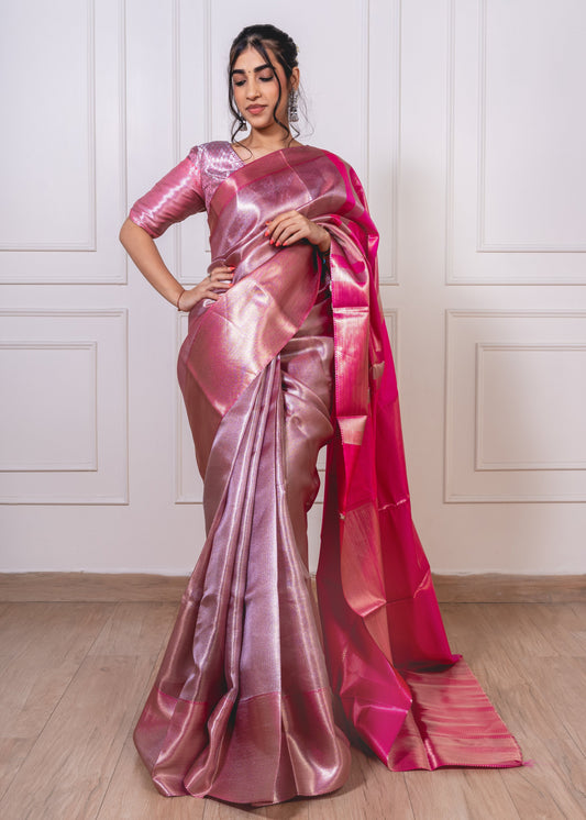 Woman wearing Jyothika-inspired pink dual-tone tissue silk saree with shimmering zari border—styled for graceful celebrations and feminine charm.
