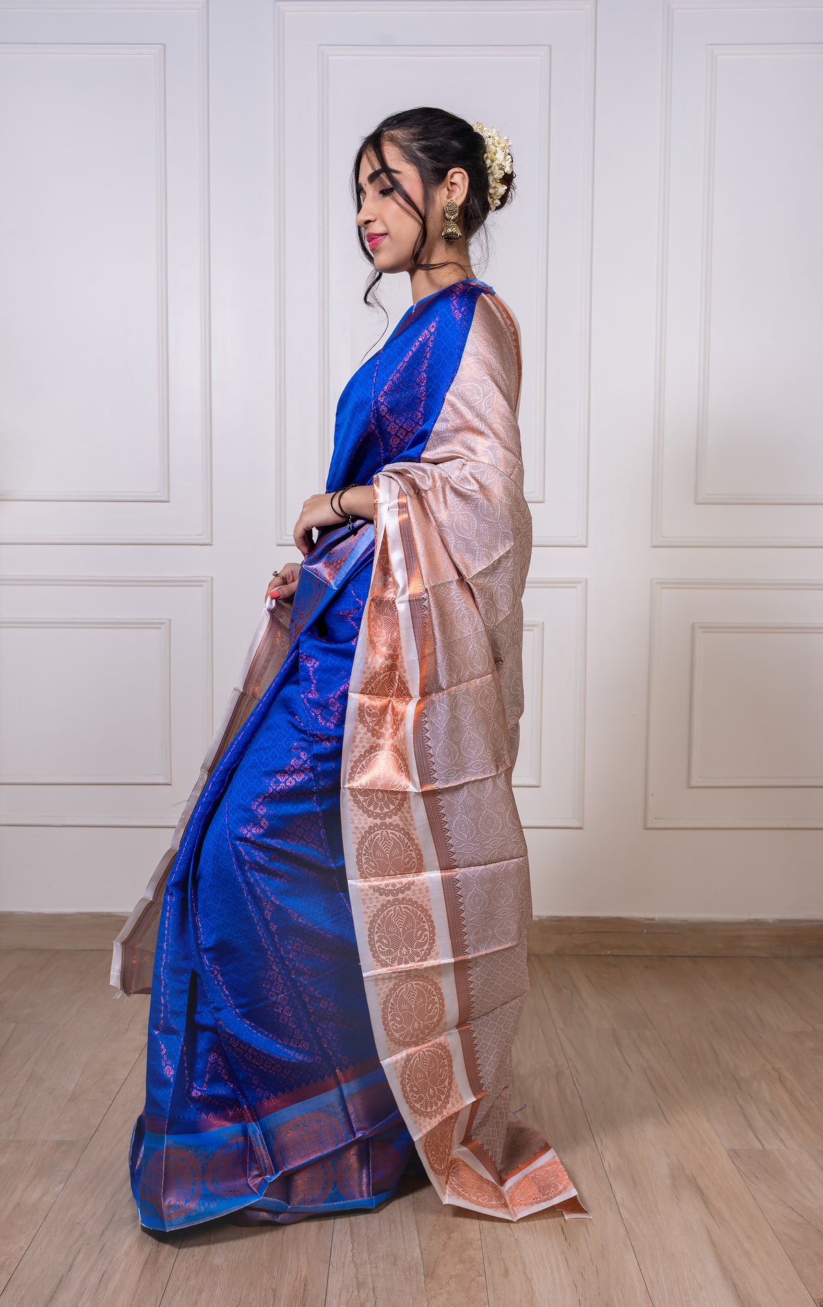 Woman wearing royal blue semisilk saree with white border and copper zari—styled for festive evenings, graceful rituals, and regal celebrations.