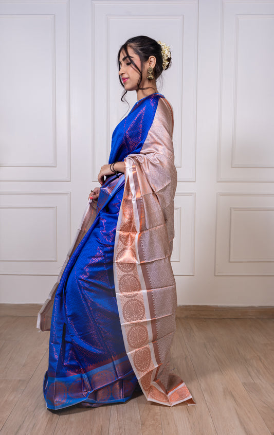 Woman wearing royal blue semisilk saree with white border and copper zari—styled for festive evenings, graceful rituals, and regal celebrations.