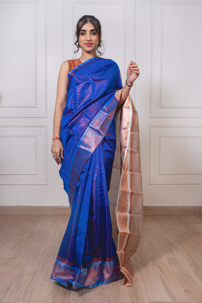 Royal blue semisilk saree with white border laid flat—showcasing rich texture and intricate copper zari weaving.