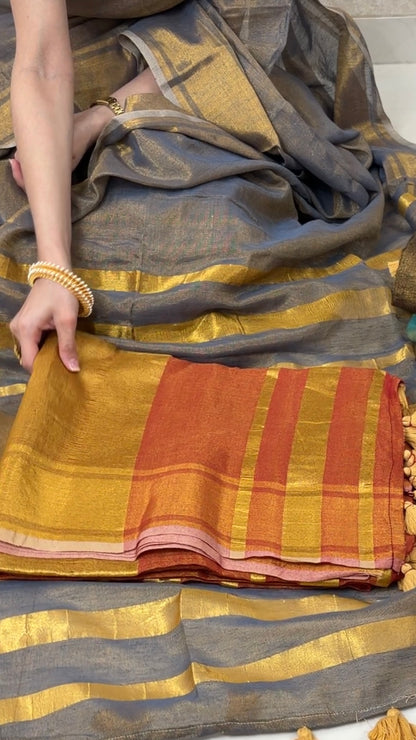 Woman displaying Orange Khadi Tissue Saree in golden tones, exuding festive elegance and grace