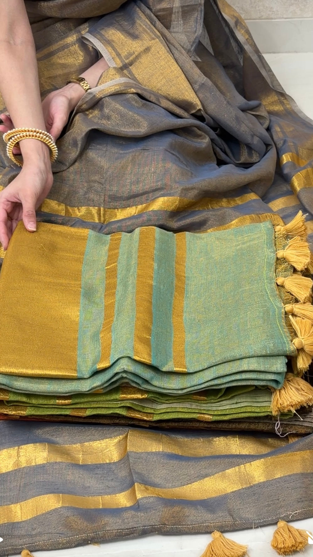 Woman displaying Teal Blue Khadi Tissue Saree in golden tones, exuding festive elegance and grace