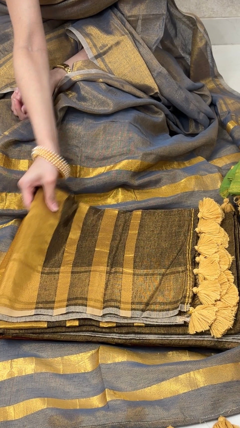 Woman displaying Brown Khadi Tissue Saree in golden tones, exuding festive elegance and grace