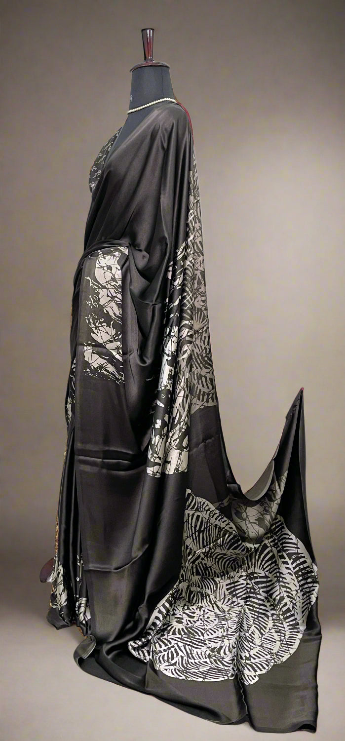 Black Modal silk saree with silver-printed pallu and crisp pleats—capturing graceful movement and statement style.
