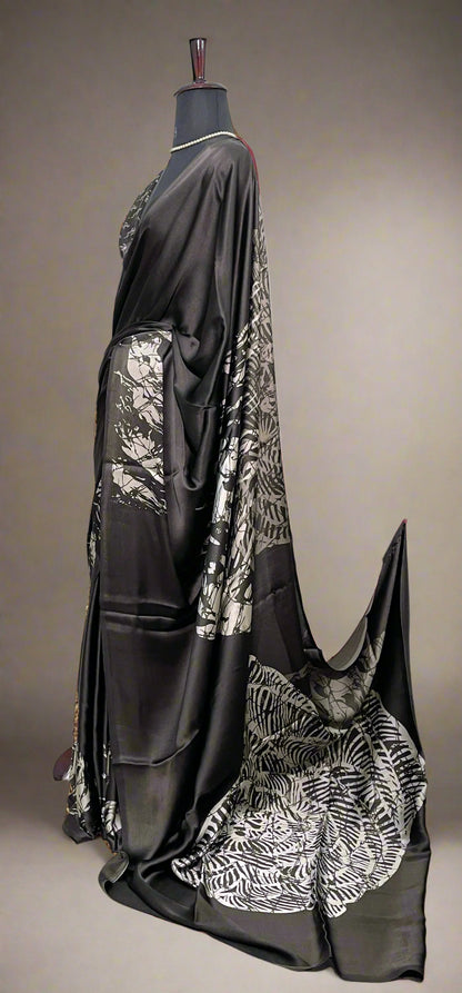 Black Modal silk saree with silver-printed pallu and crisp pleats—capturing graceful movement and statement style.