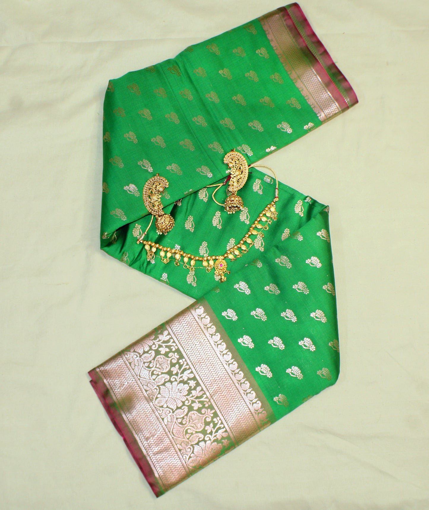 - Close-up of golden zari on green semi silk saree—highlighting traditional craftsmanship and radiant texture.