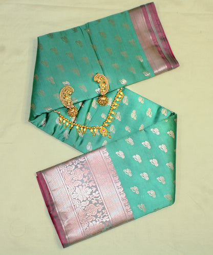 Close-up of golden zari on teal green semi silk saree—highlighting intricate craftsmanship and jewel-toned shimmer.