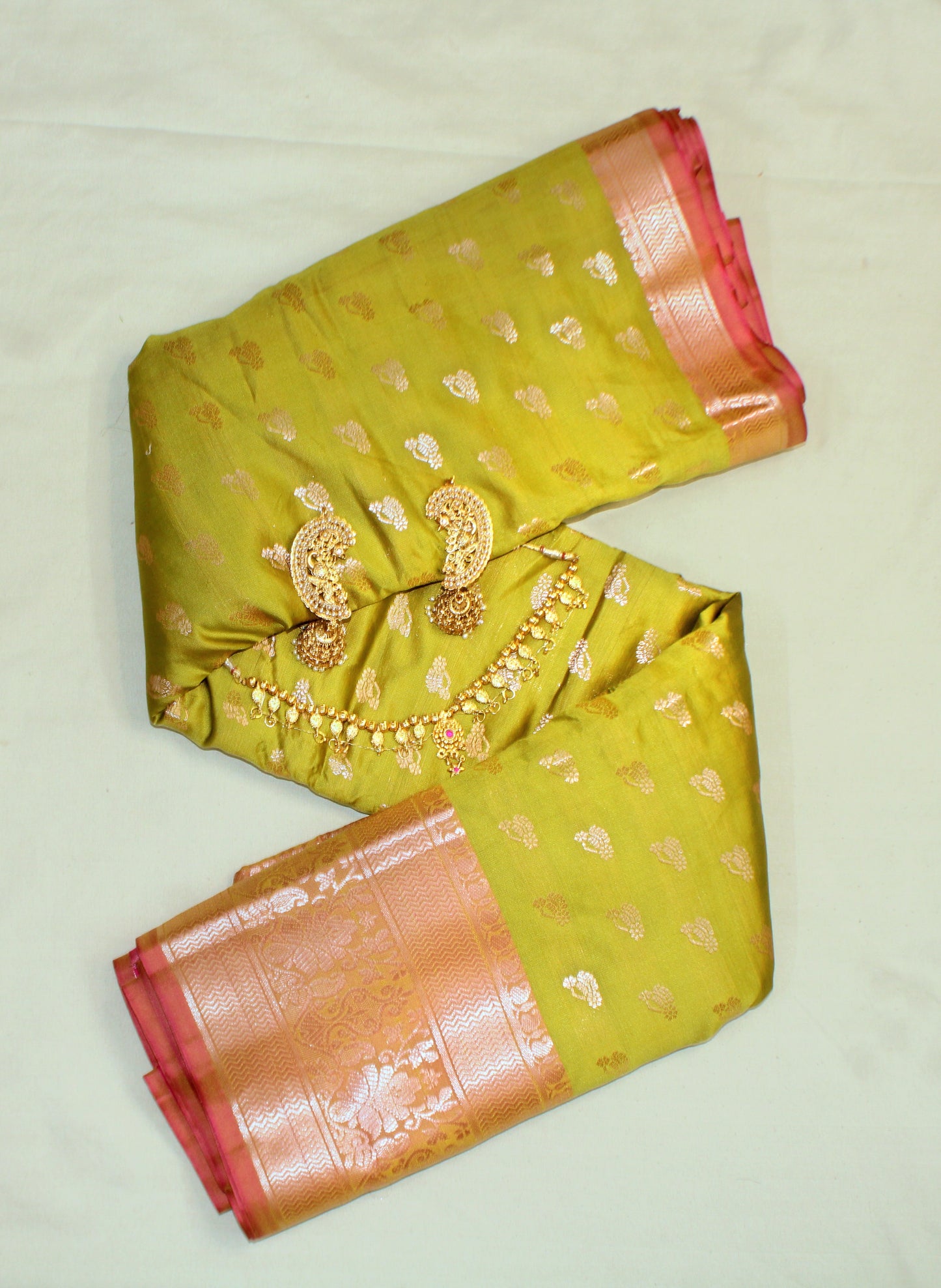 Close-up of golden zari on mehndi green semi silk saree—highlighting earthy elegance and festive shimmer.