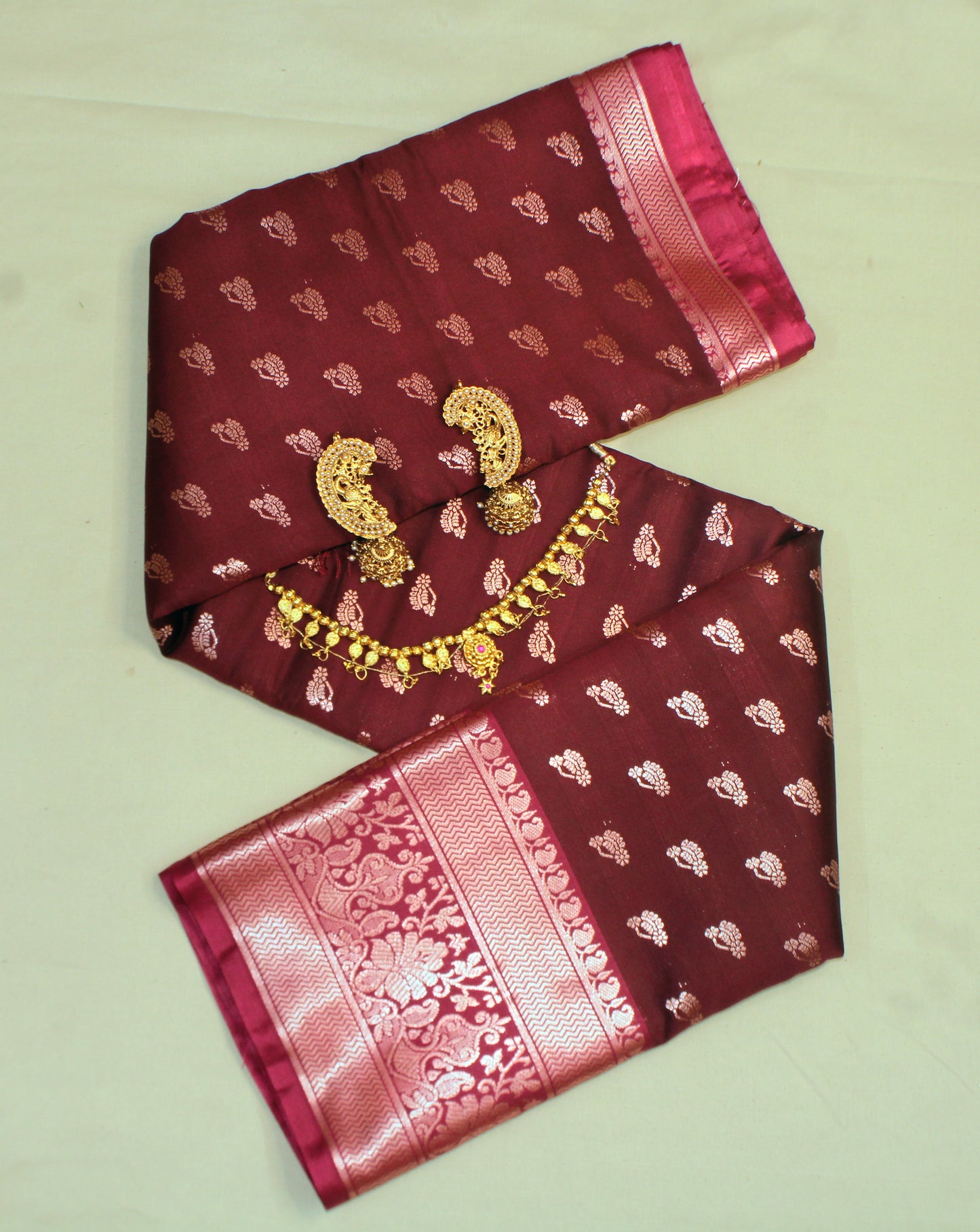 Close-up of golden zari on maroon semi silk saree—highlighting dramatic contrast and fine craftsmanship