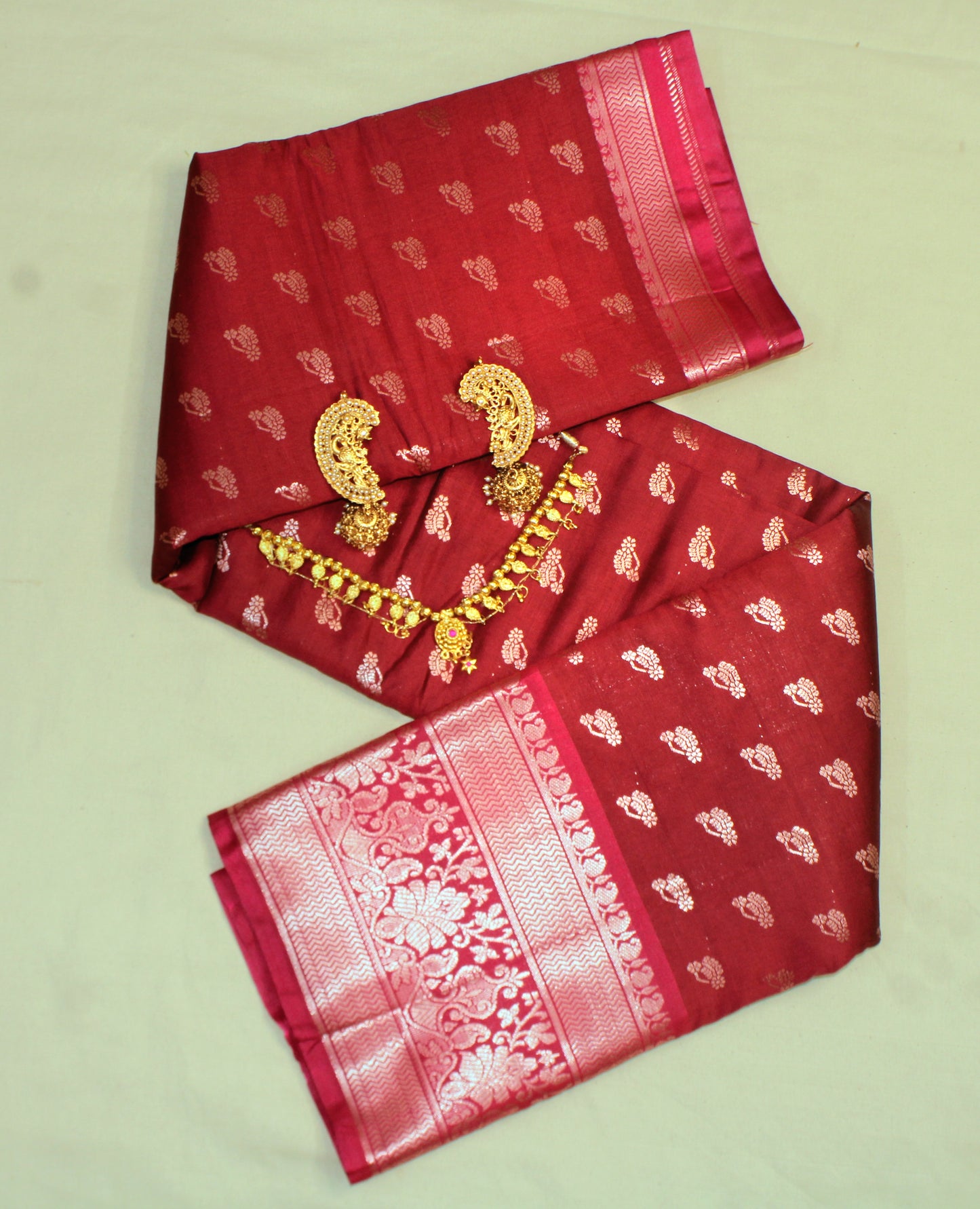 Close-up of golden zari on red semi silk saree—highlighting rich texture and ceremonial elegance.