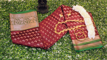 Maroon Chandrakor Butta saree laid flat, showcasing intricate crescent weaves and deep ceremonial tone.