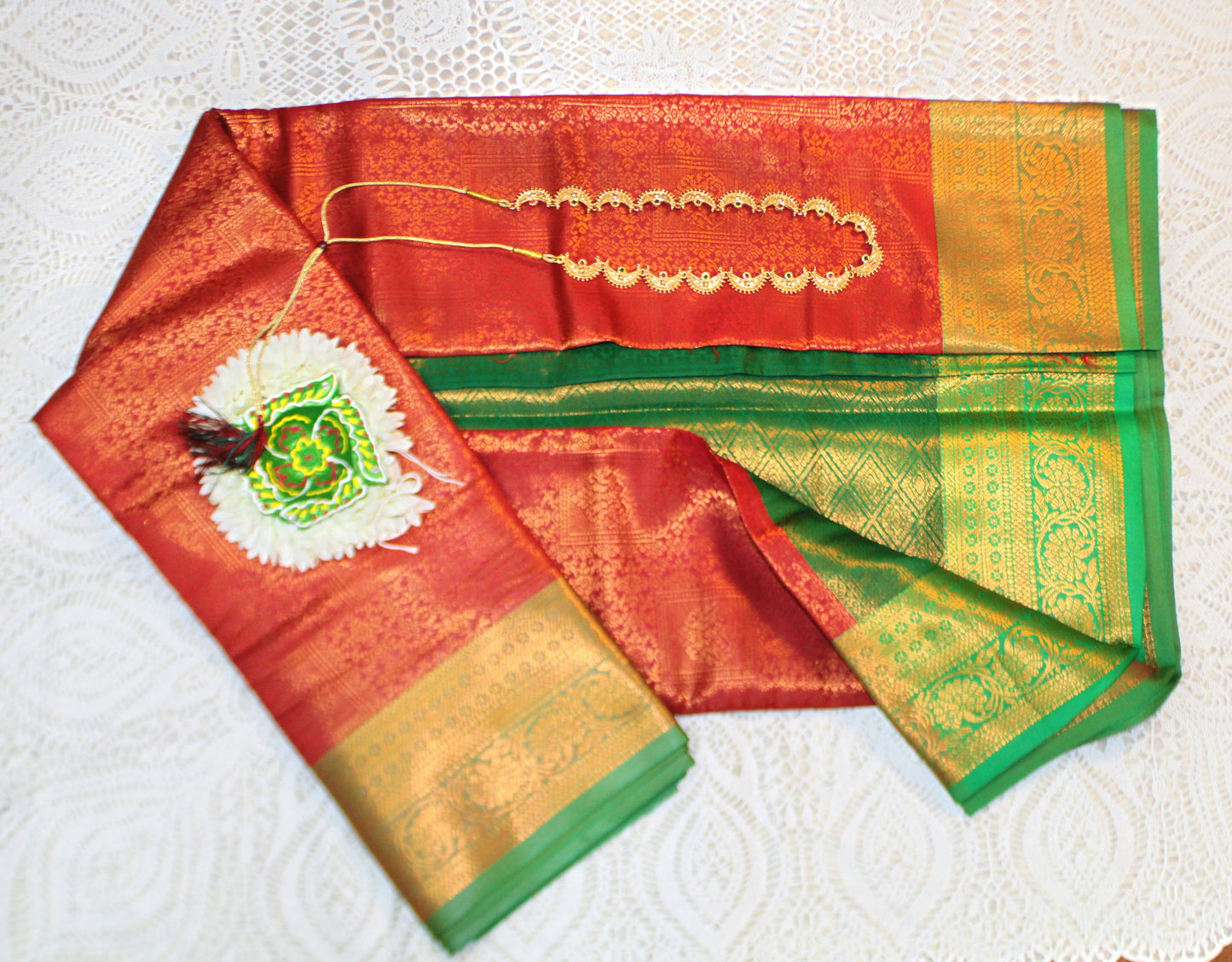 Close-up of golden zari on red semi silk saree—highlighting rich texture and ceremonial elegance.
